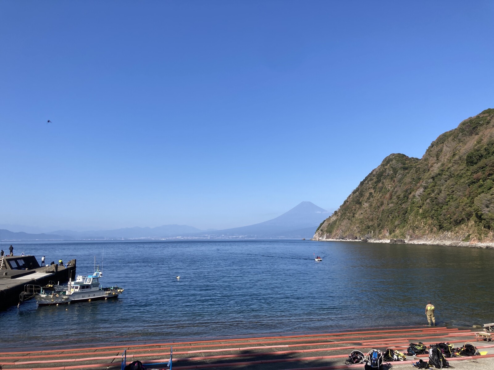西伊豆井田の海から望む富士山と駿河湾、ダイビング器材が並ぶ海岸の風景