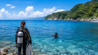 夏の伊豆の海を前に、ダイビング器材を背負ってエントリー準備をするダイバー